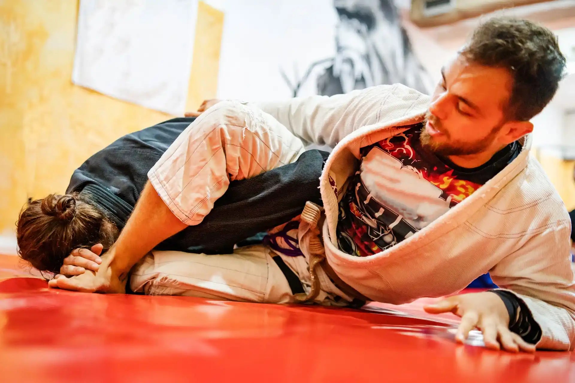 Two individuals in a martial arts position on a red mat.
