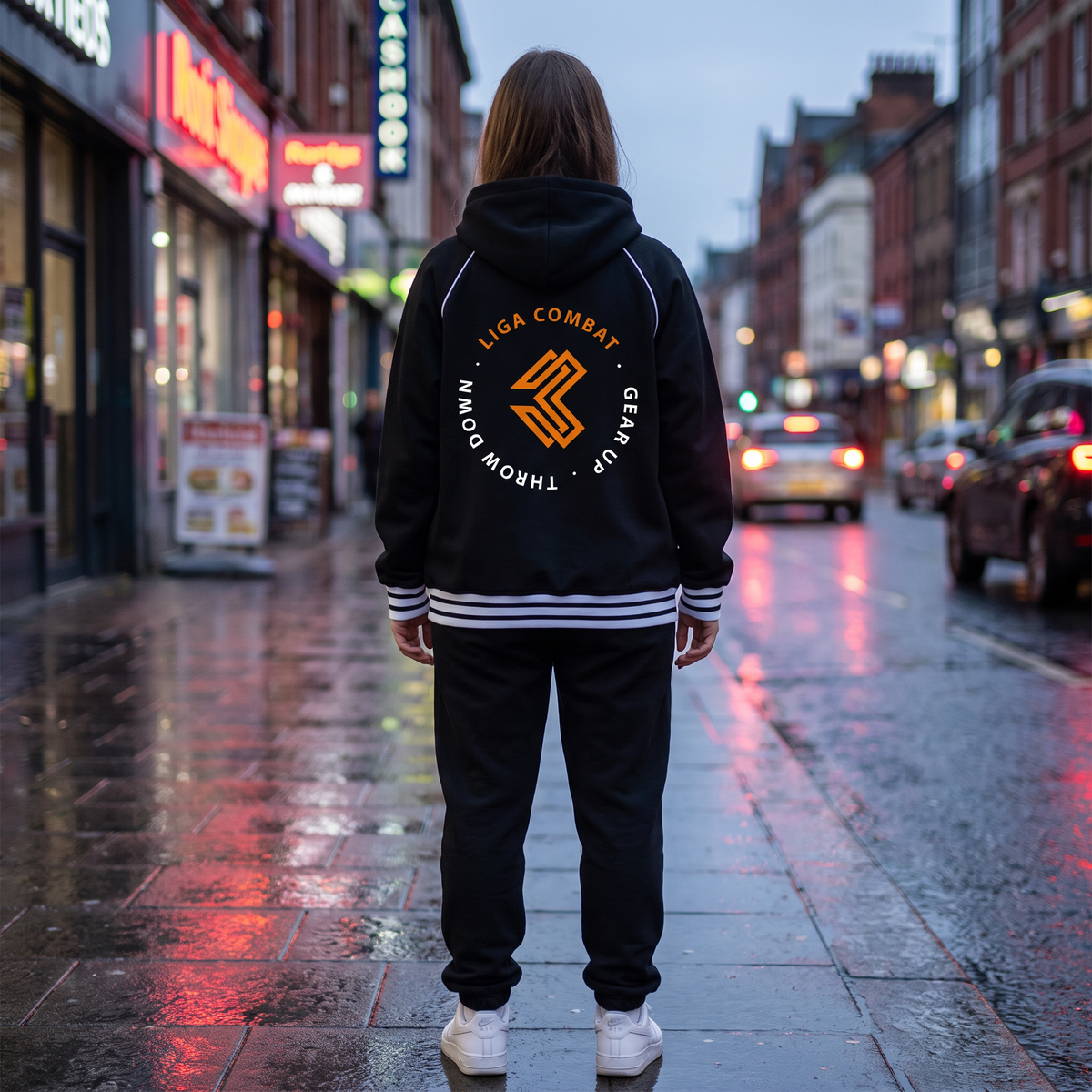 Liga Combat Varsity Mantra Jacket in black from behind on a wet city street, circular back crest
