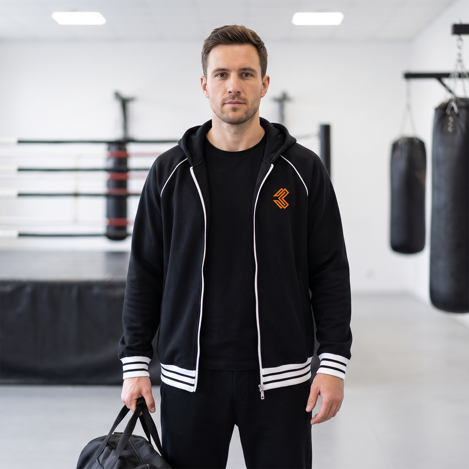 Liga Combat Varsity Mantra Jacket in black worn in a boxing gym with a training bag