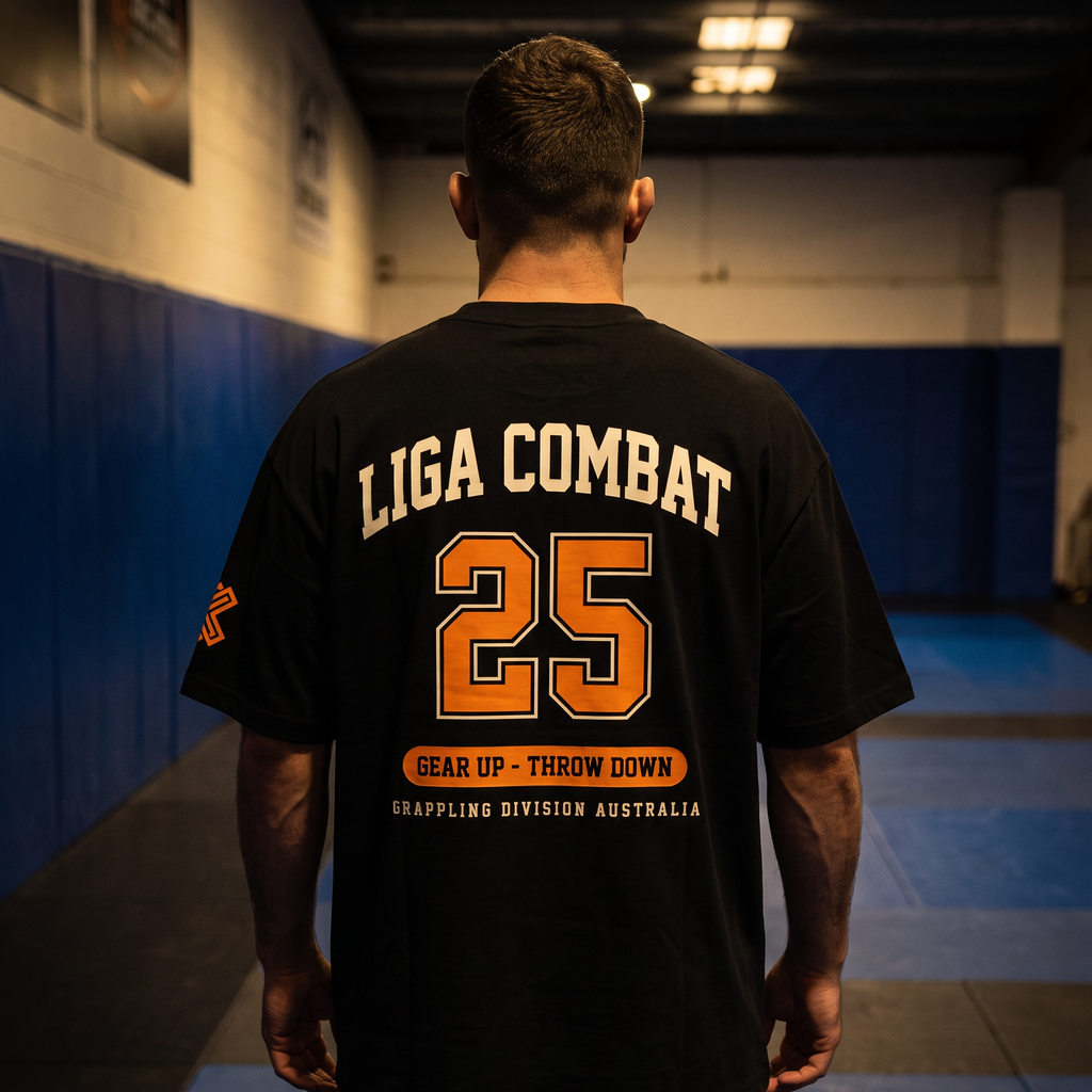 Liga Combat Varsity 25 Tee worn back-on in the gym, full collegiate print visible