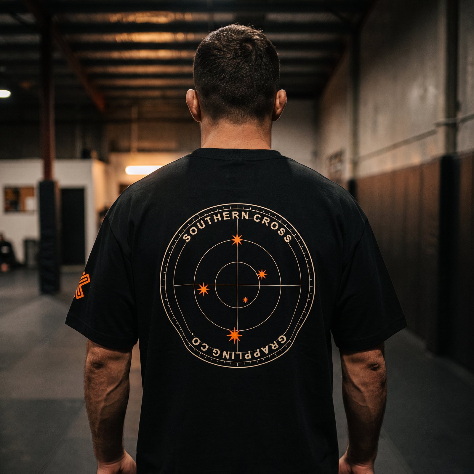 Liga Combat Southern Cross Grappling Tee worn back-on in the gym, full compass emblem visible