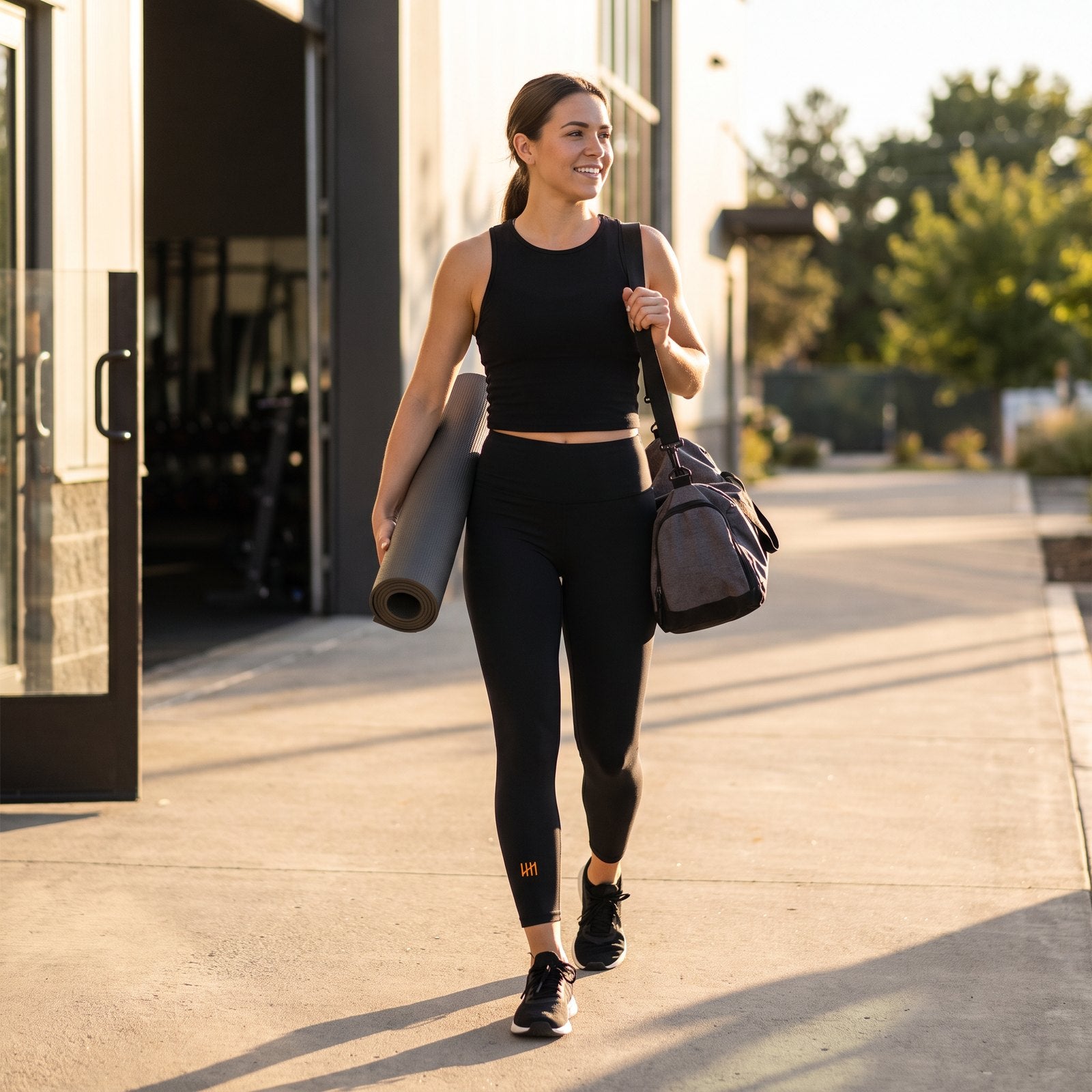 Liga Combat Mat Hours Legging worn walking out of the gym at golden hour with a rolled mat