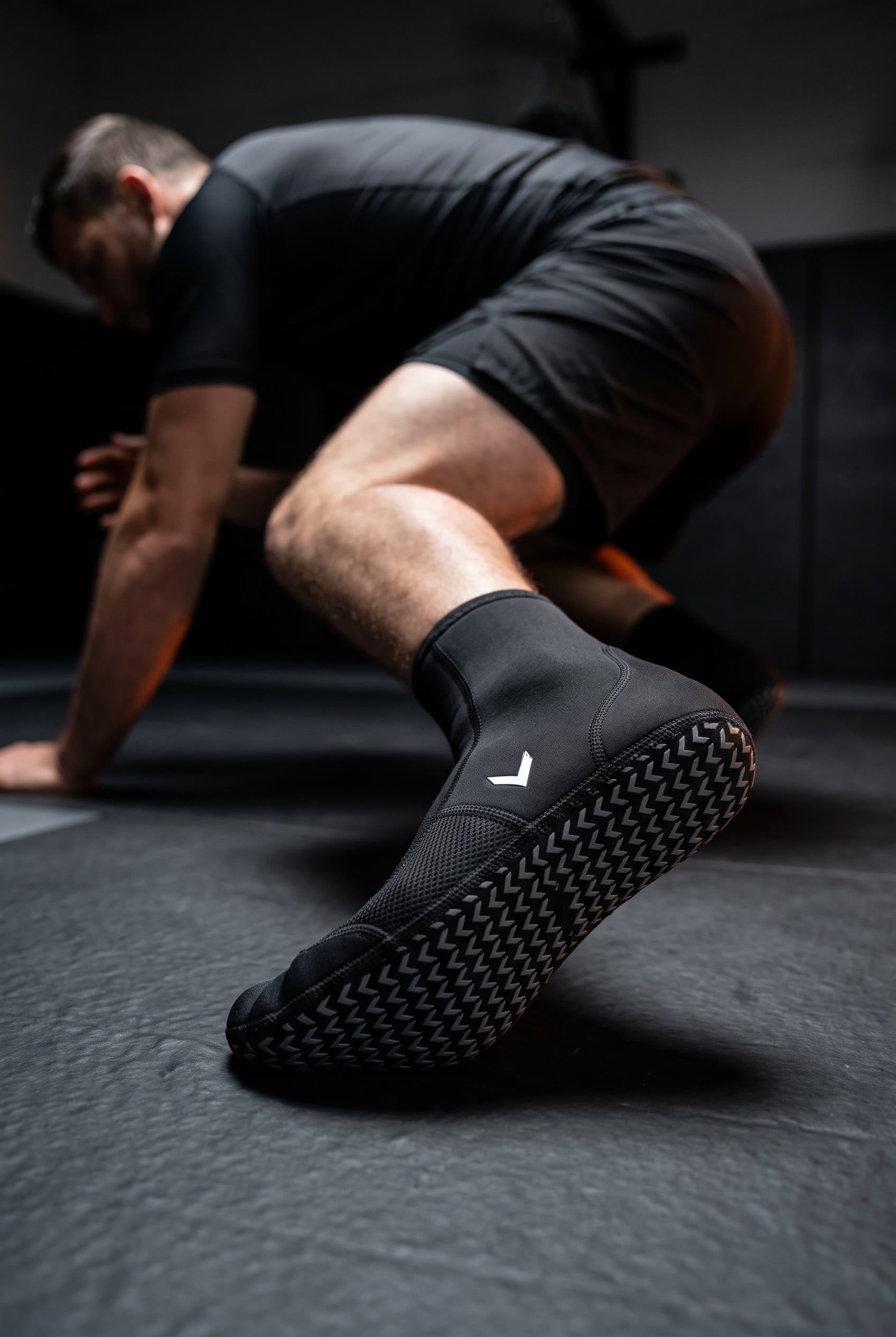 Grappler driving out of a scramble on the mat, the chevron grip sole of the Liga Combat grappling sock facing camera